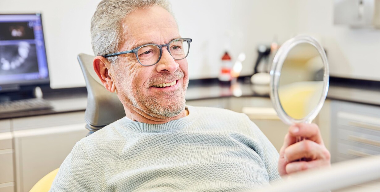 Middle Age Patient schaut lächelnd in den Spiegel